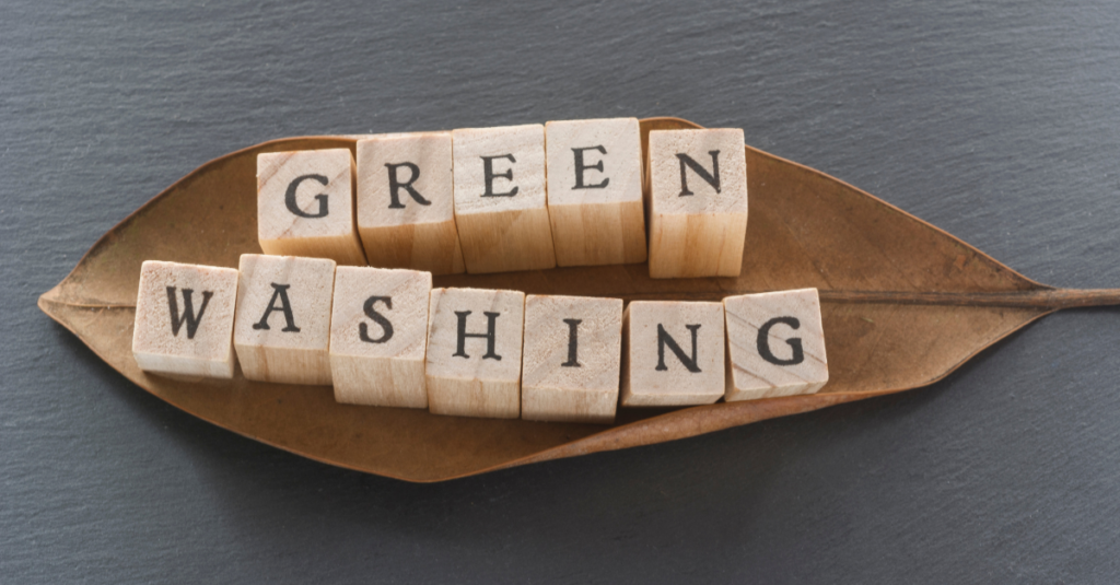 Blatt auf dem Holzwürfel mit Buchstaben liegen, die das Wort Greenwashing bilden